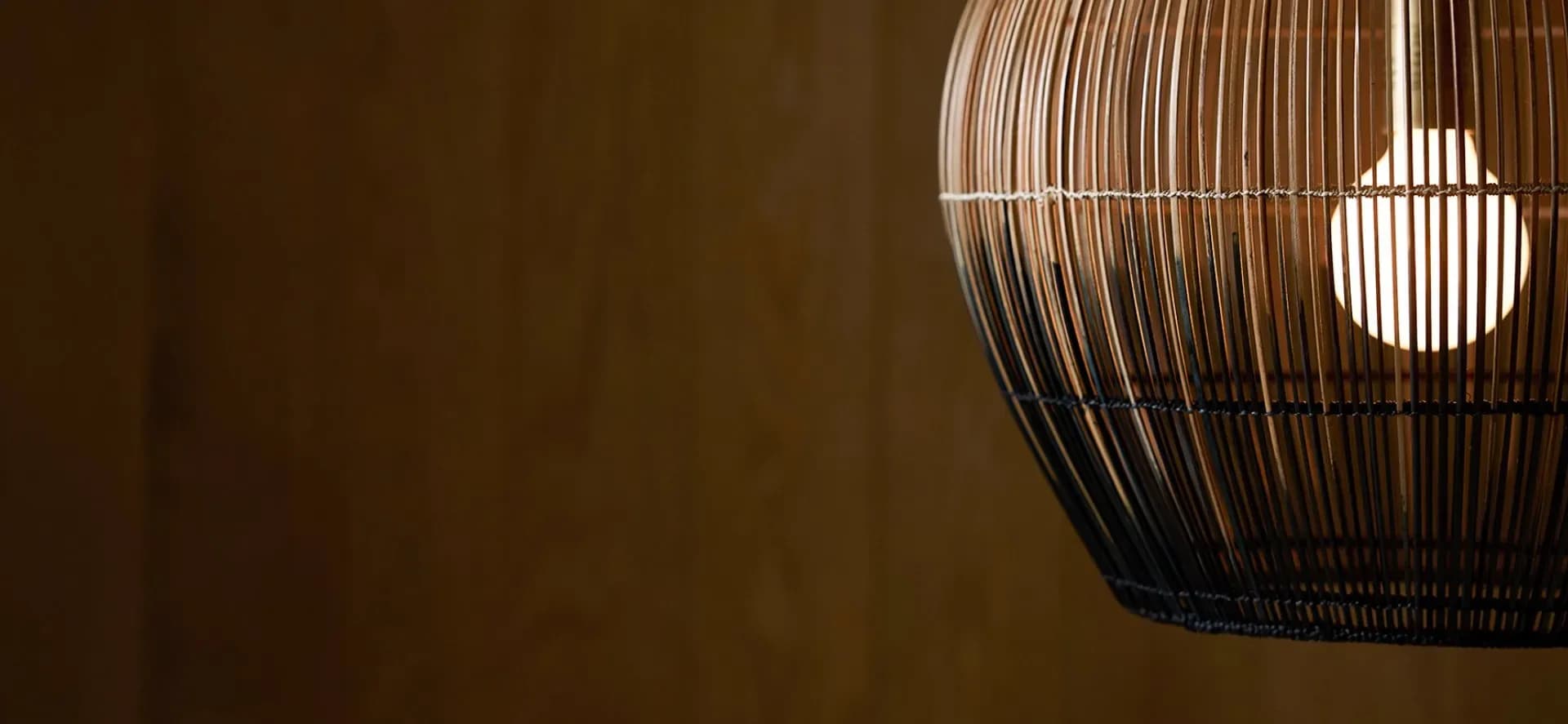Glowing wooden slat pendant lamp against a warm dark interior